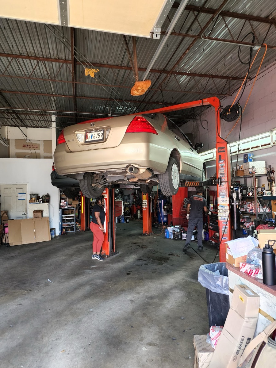 A Honda up on the lift with two technicians working in the Apna Garage service bay